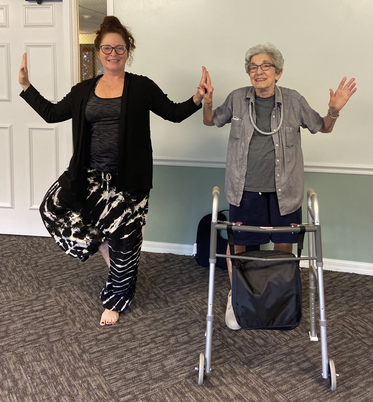 Lisa and an older student practicing a supported balance pose beside a walker