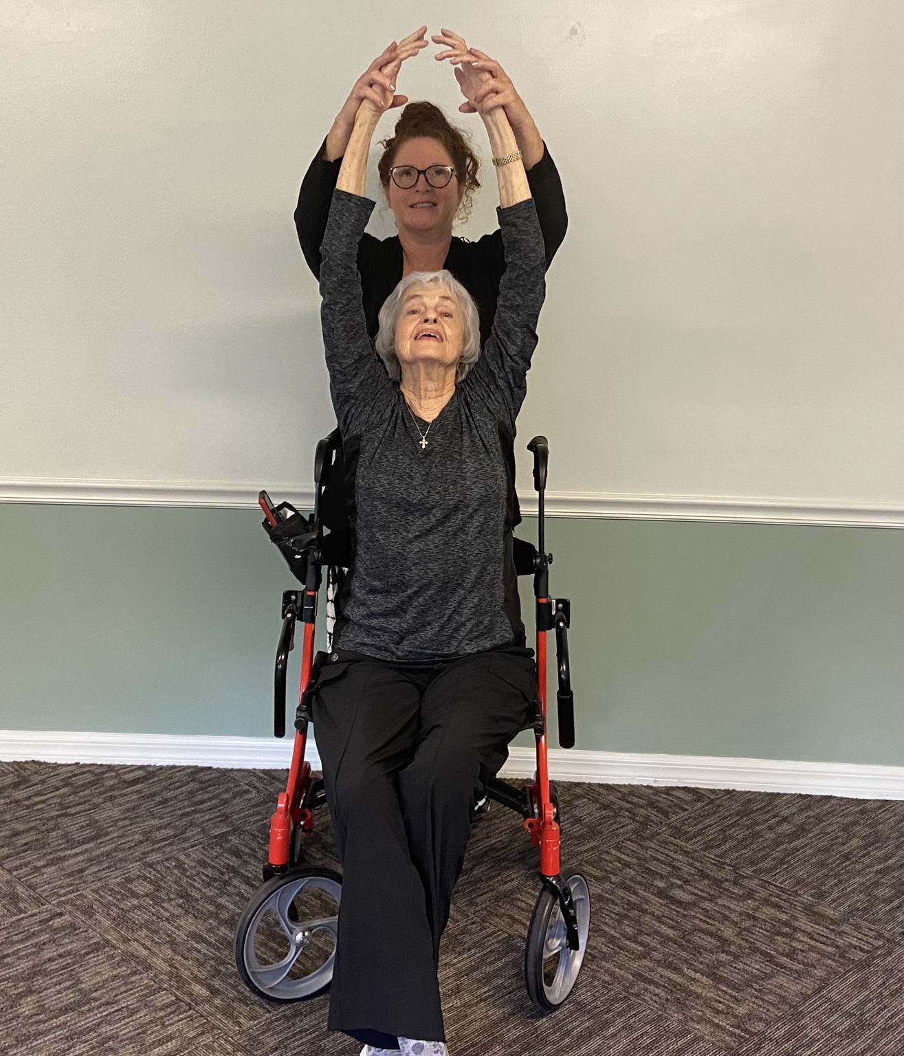 Lisa guiding an older wheelchair user through an accessible overhead arm movement