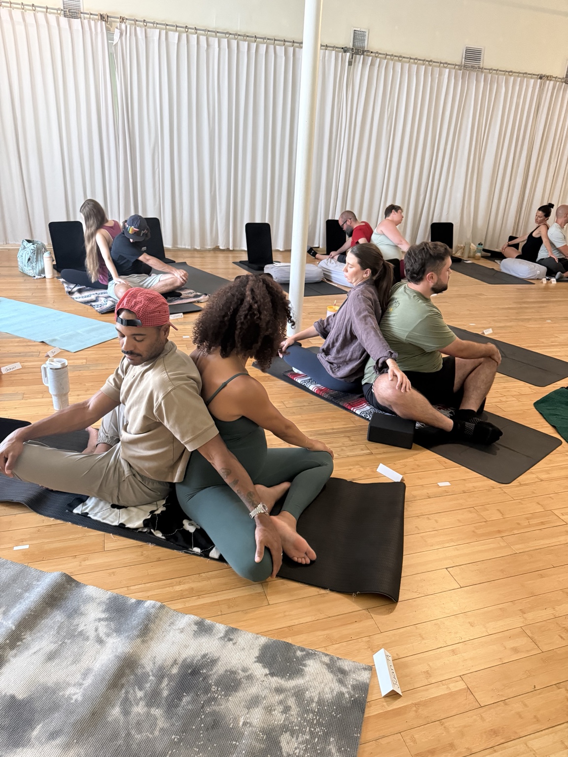 Partners practicing supported seated movement together in a yoga workshop