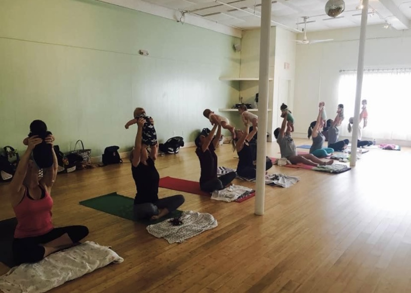 Parents lifting their babies together during a postnatal yoga class