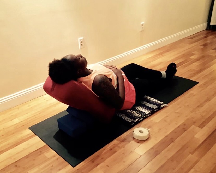 A student resting in a supported reclining restorative yoga pose