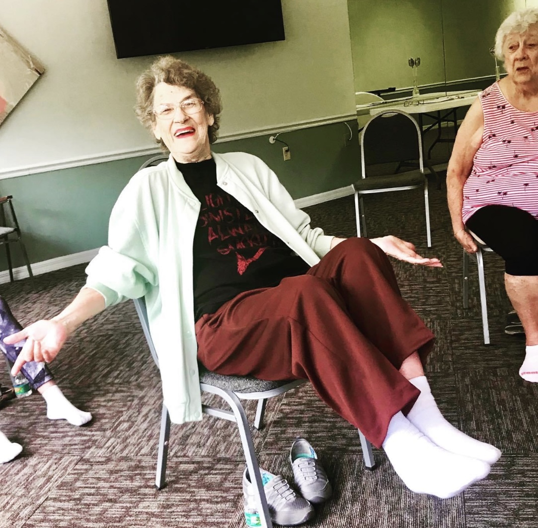 An older student smiling during a seated movement class